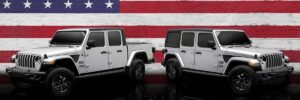 A Jeep Gladiator and Jeep Wrangler Unlimited standing in front of an American flag. 