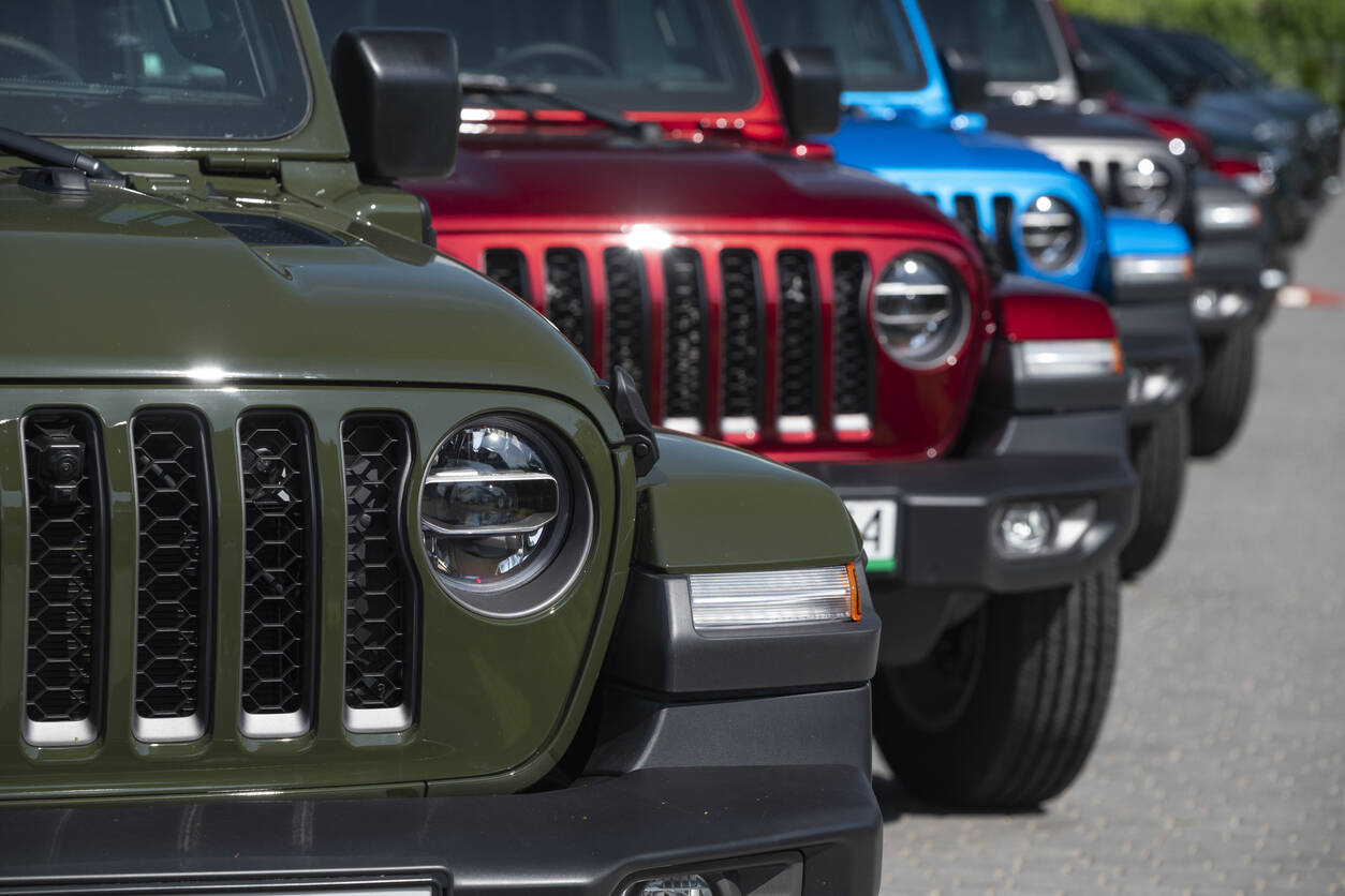 Jeep wranglers of varying different colors lined up in parking lot