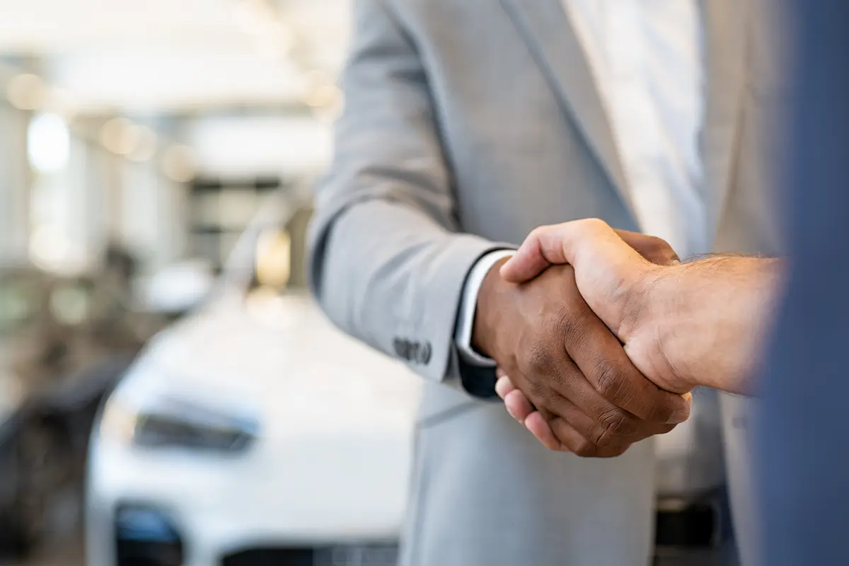 Car salesman and client handshake.